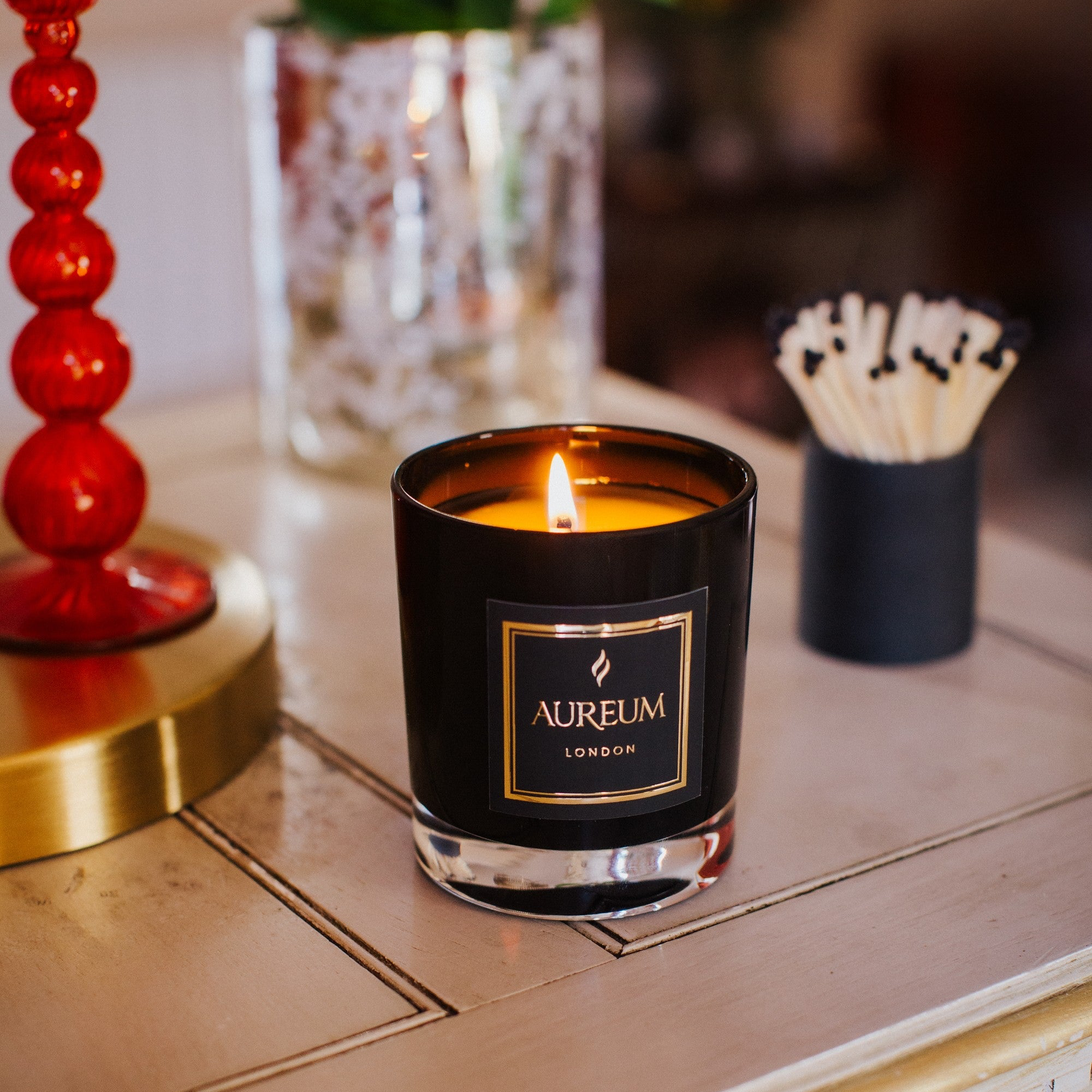 Aureum candle on a table with decorative items in the background