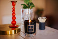 Load image into Gallery viewer, Candle with 'Aureum London' label on a table with decorative items.
