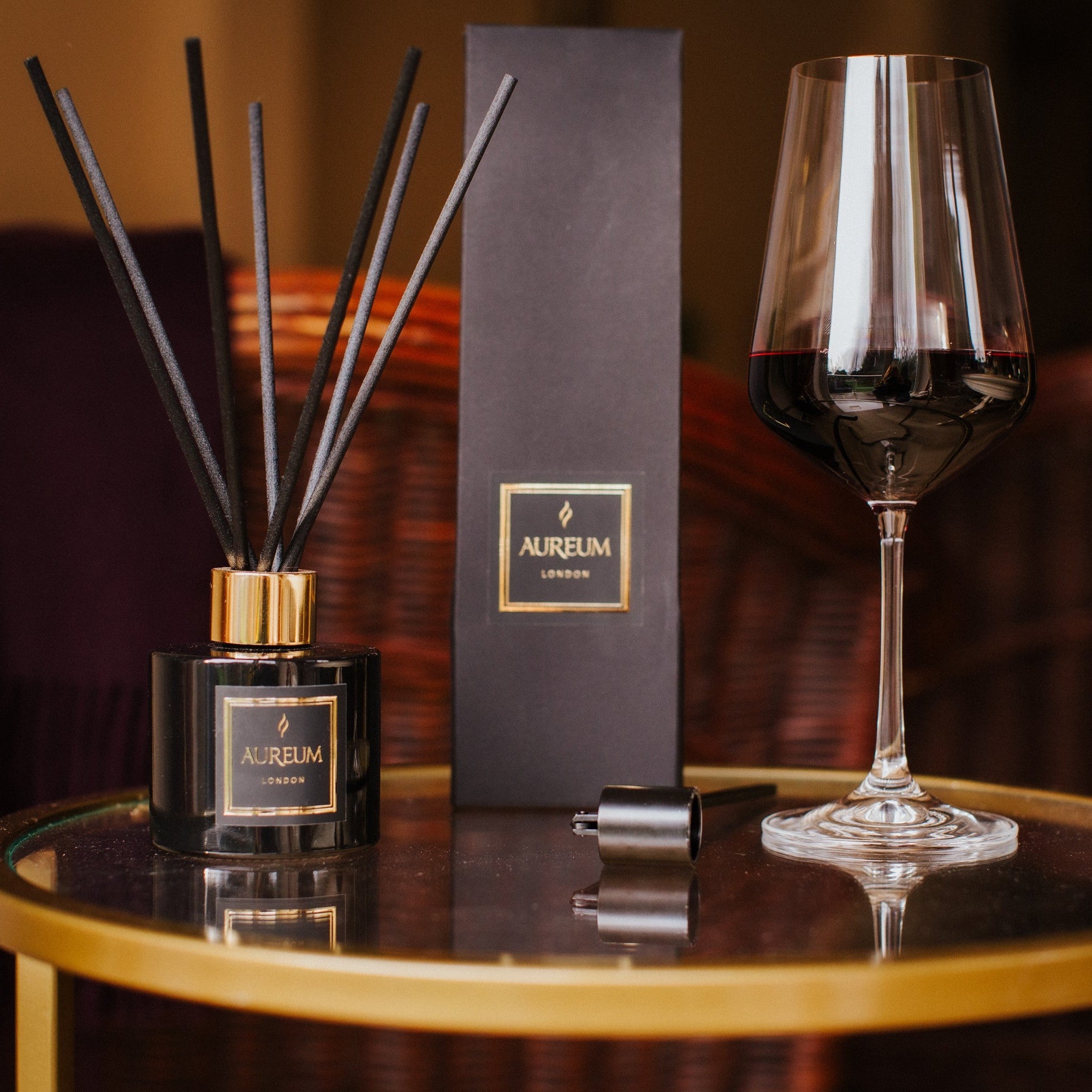Aromatherapy diffuser, box, and wine glass on a table with a blurred background
